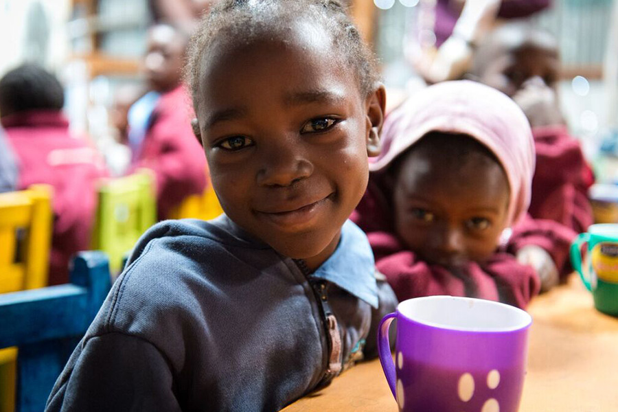 two young children sit at table with cup