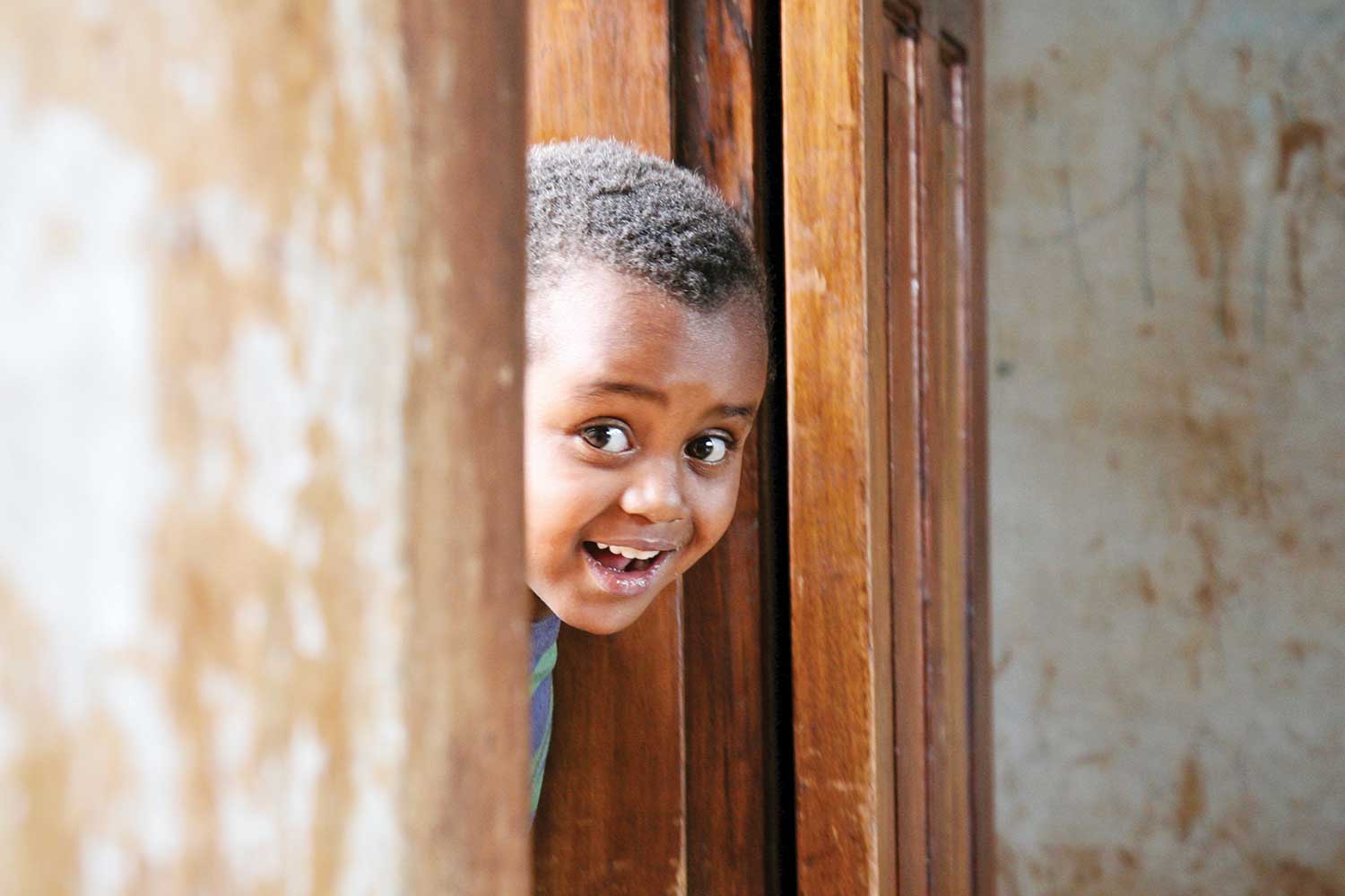 little boy poking head out of door for photo