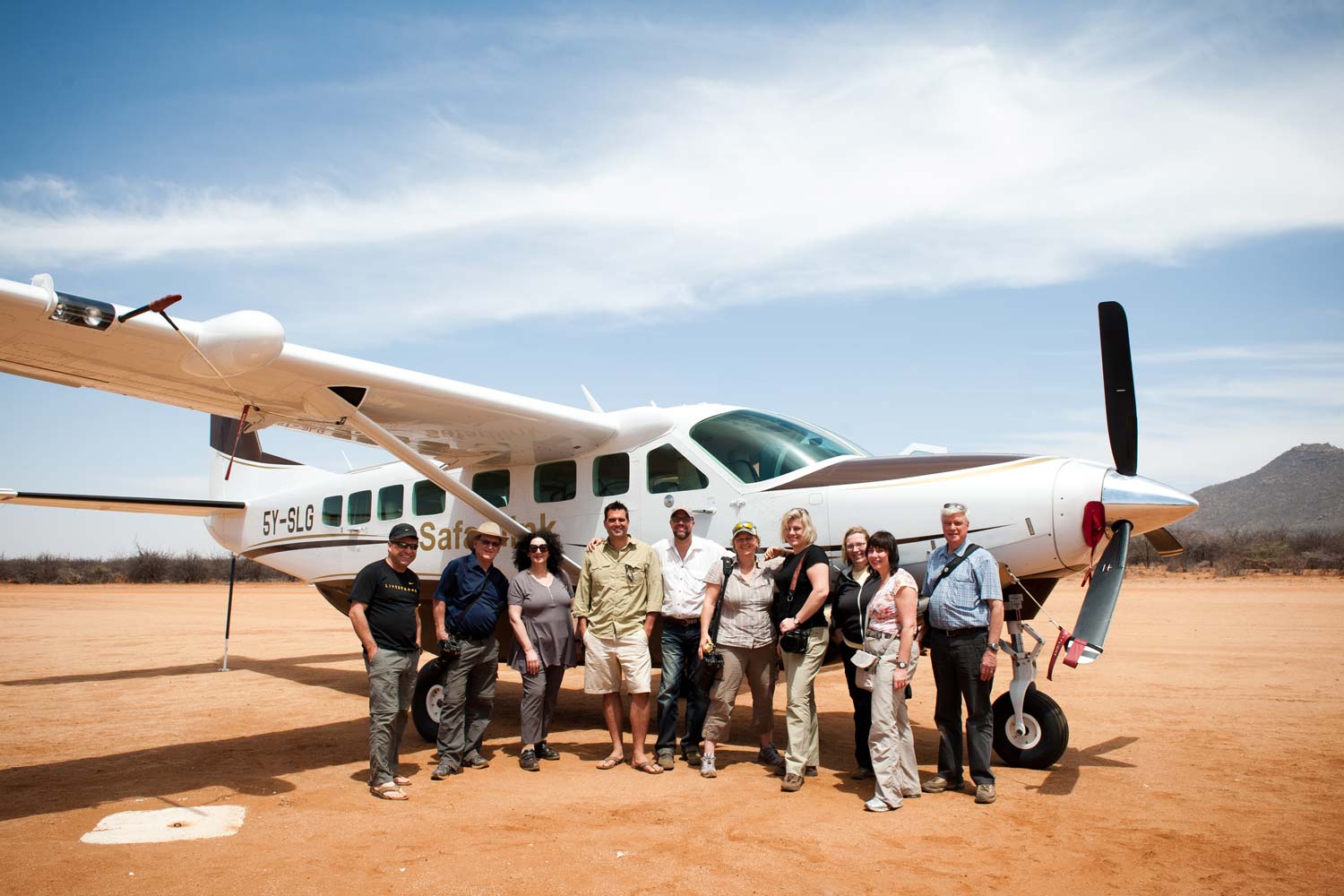 ten travellers in front of plane for safari