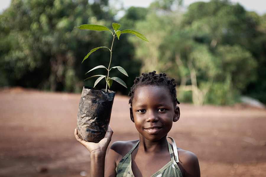 young child holding up plant ready to grow