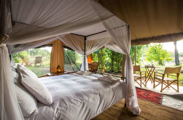 double bed in large luxury tent with flaps rolled up